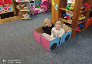 Dzieci siedzą w samochodzie zrobionym z pudełka